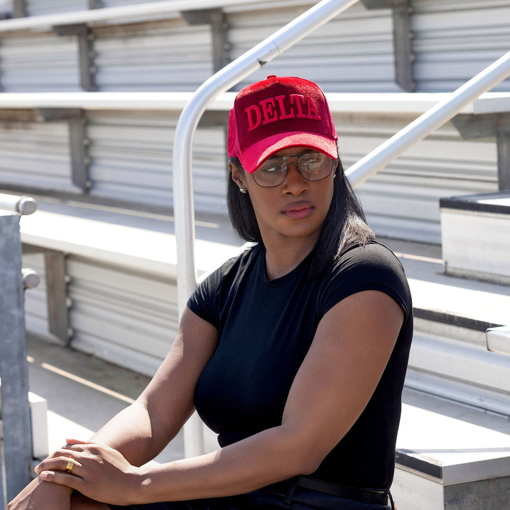 Person wearing a red 'DELTA' cap sitting on bleachers