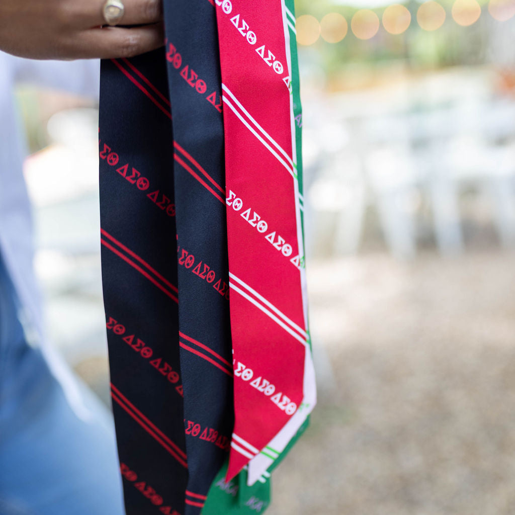 Three neckties with text held by a person outdoors