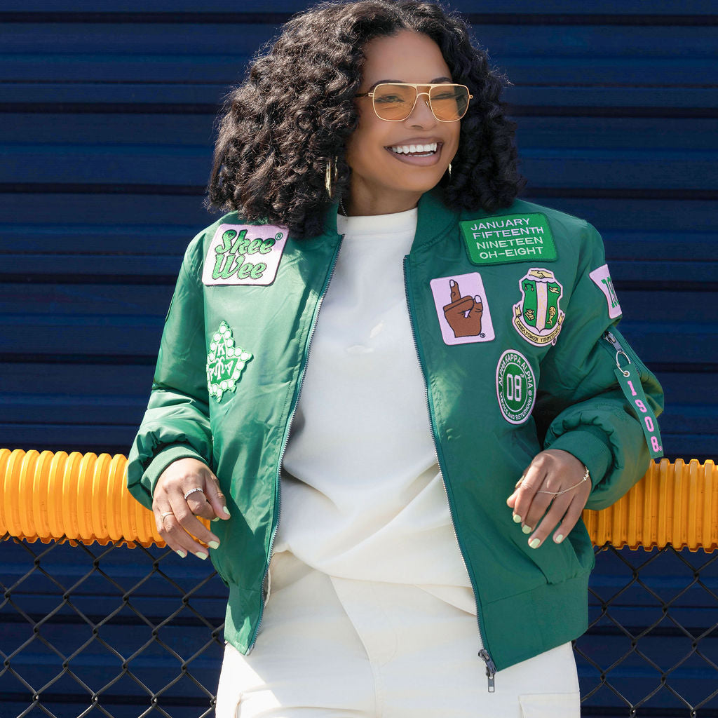 Woman wearing a green jacket with patches against a blue background