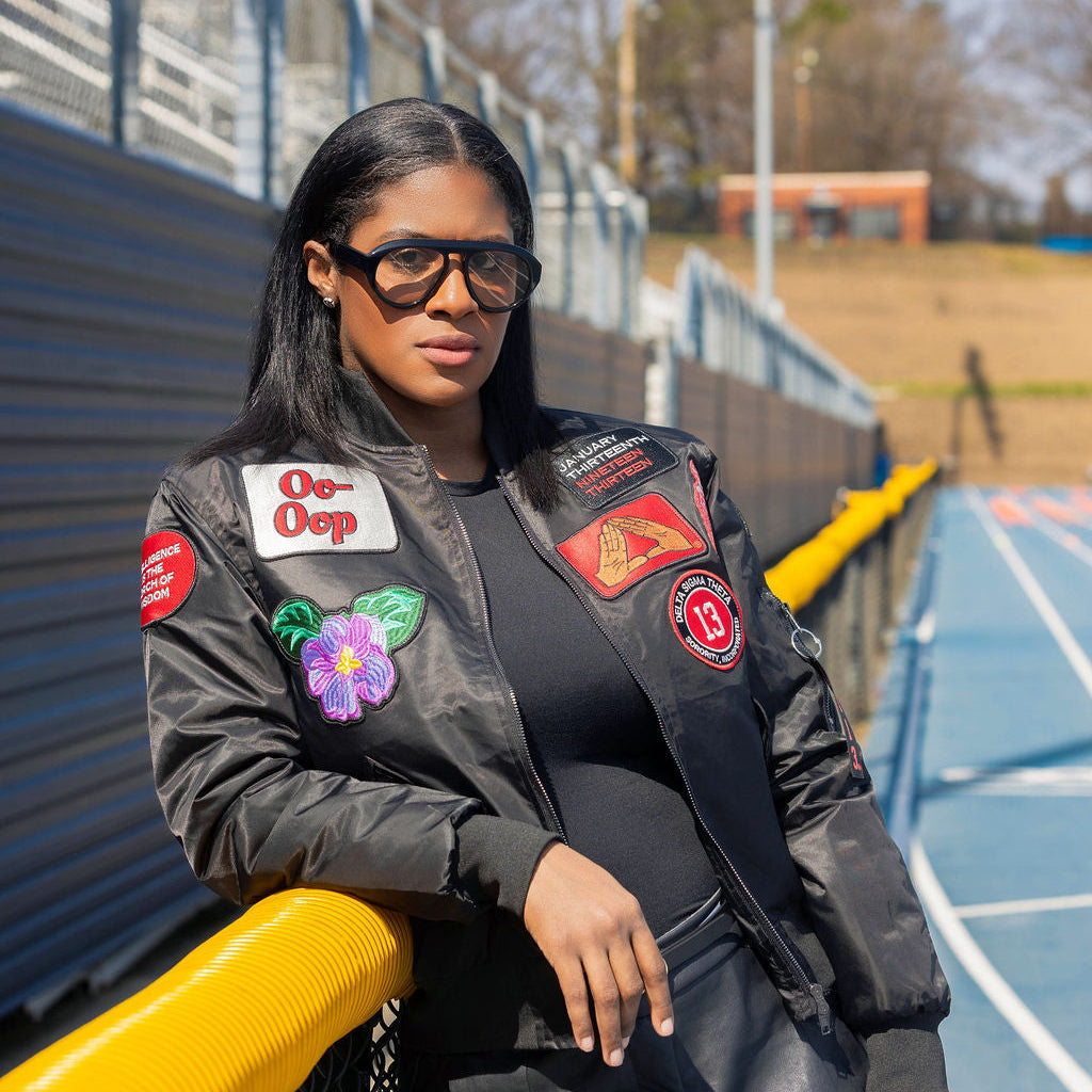 Woman wearing a jacket with patches on a track and field background