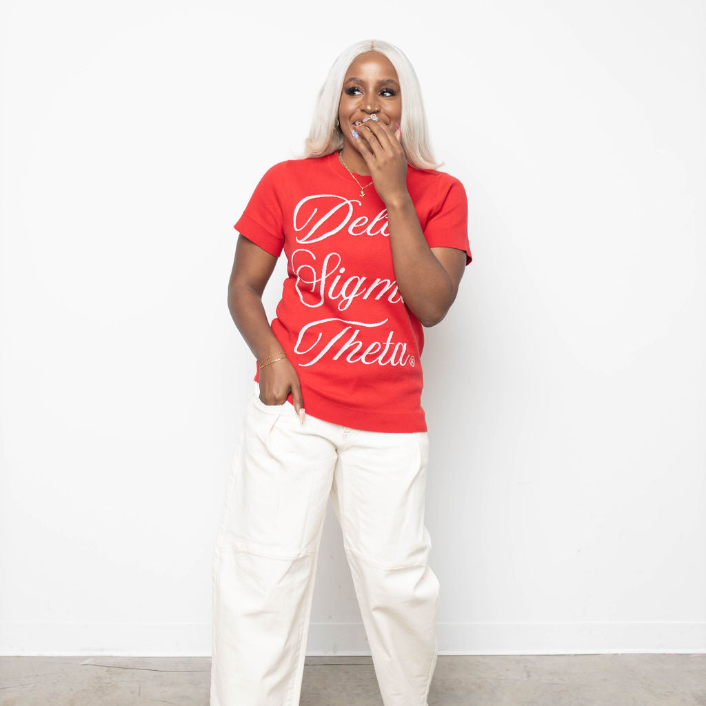 Person wearing a red knit with white text and white pants against a white background