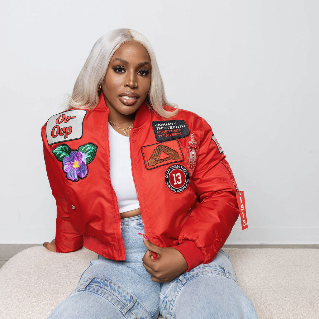 Woman wearing a red jacket with delta sigma theta related patches on a white background