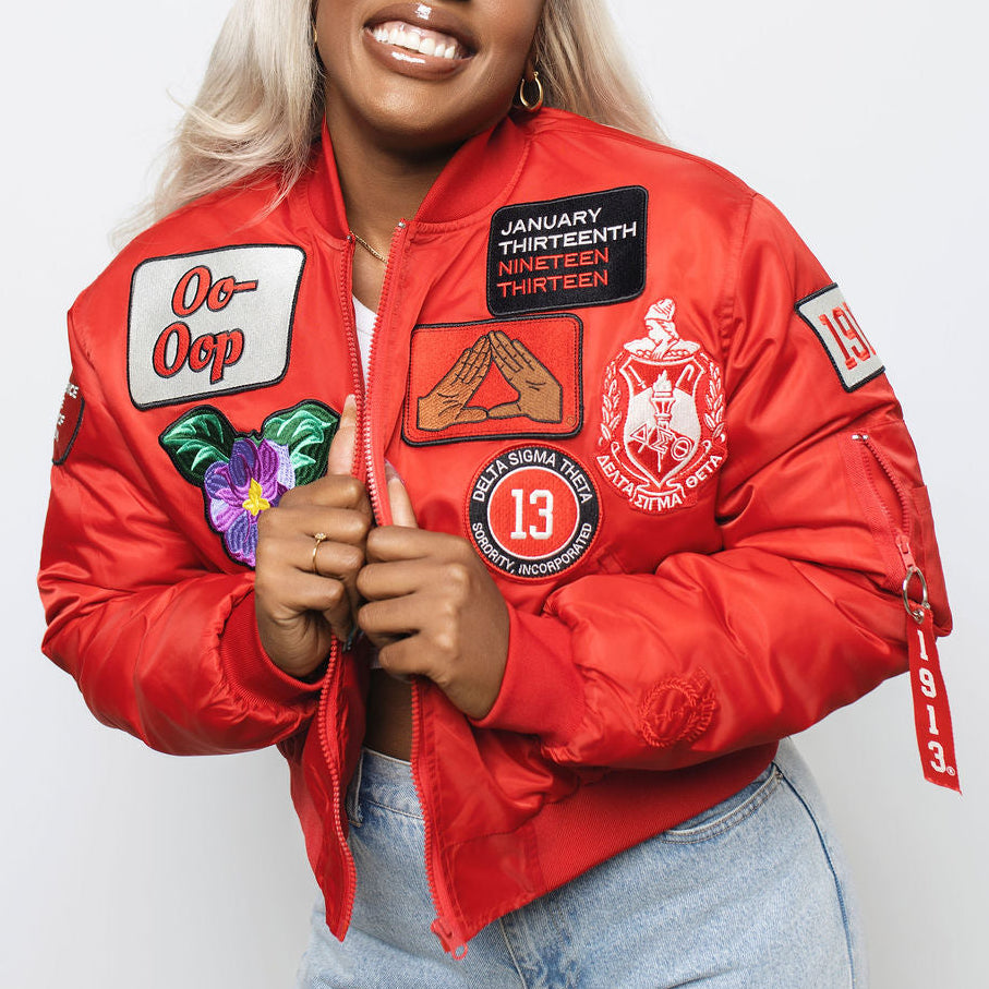 Person wearing a red jacket with delta sigma theta related patches on a white background