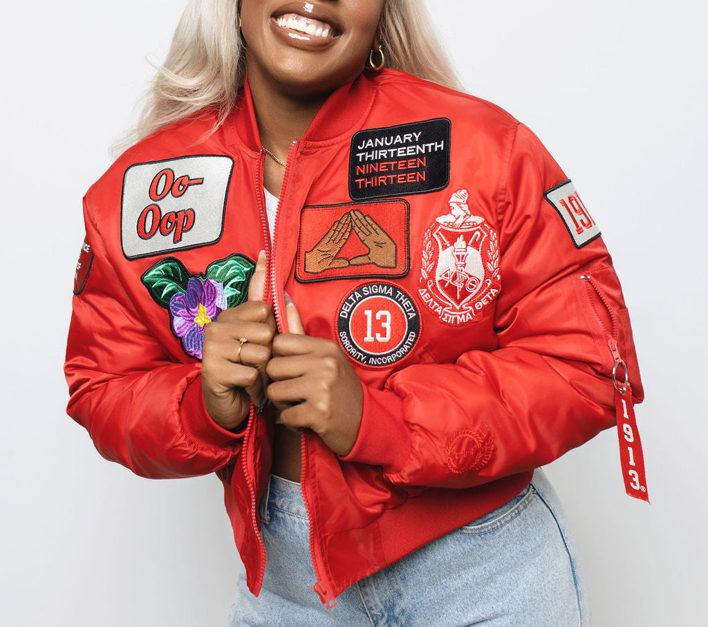 Person wearing a red jacket with delta sigma theta related patches on a white background