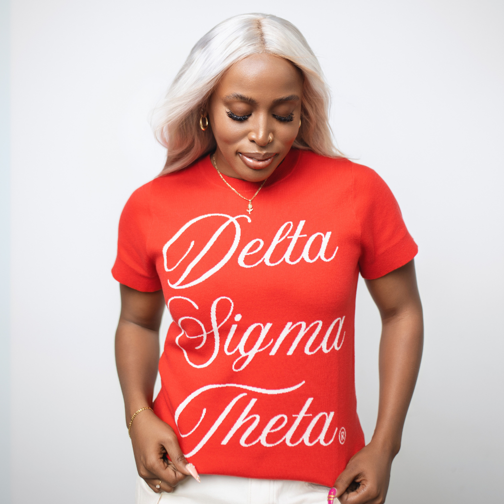 Person wearing a red 'Delta Sigma Theta' knit short sleeved sweater on a plain background