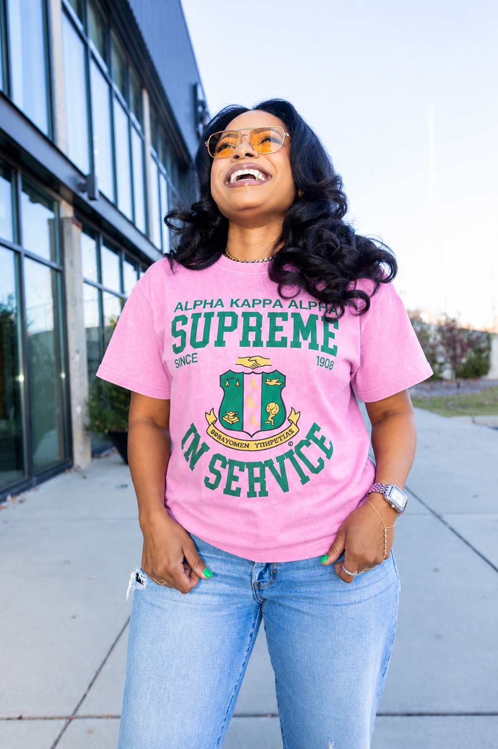 Person wearing a pink t-shirt with green text and graphics, standing outdoors.
