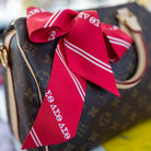 Designer handbag with a red ribbon bow on a colorful surface