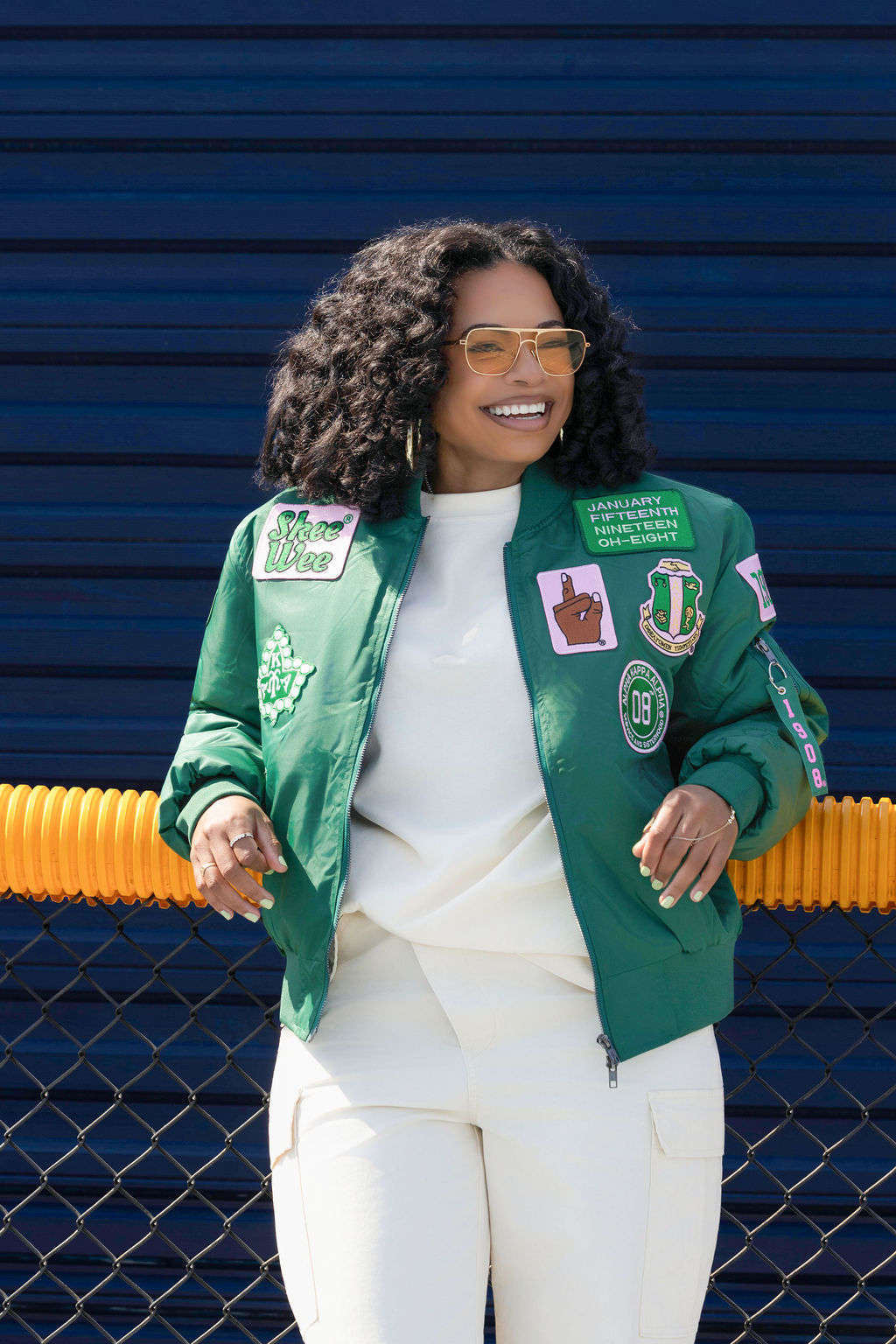 Woman wearing a green jacket with patches against a blue background