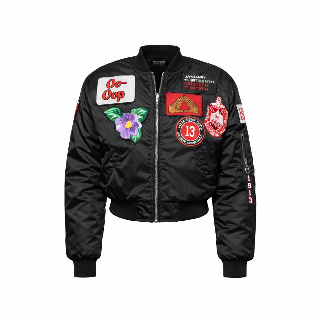 Black bomber jacket with various colorful patches on a white background