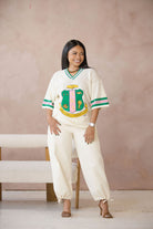 Woman wearing a white sports jersey with a AKA shield on a beige background