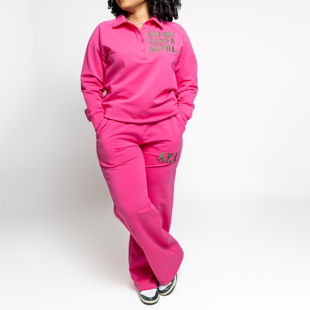 woman in pink pant set with green alpha kappa alpha text on left chest and AKA on pant leg