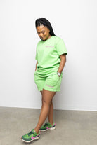 Person wearing a bright green outfit with matching shoes on a plain background