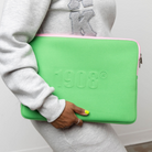 Person holding a green laptop sleeve with '1908' branding.