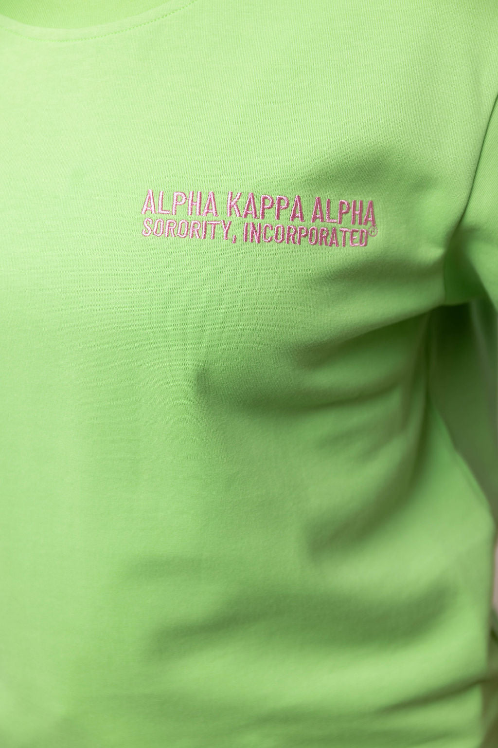 Green shirt with 'Alpha Kappa Alpha Sorority, Incorporated' text in pink on a plain background